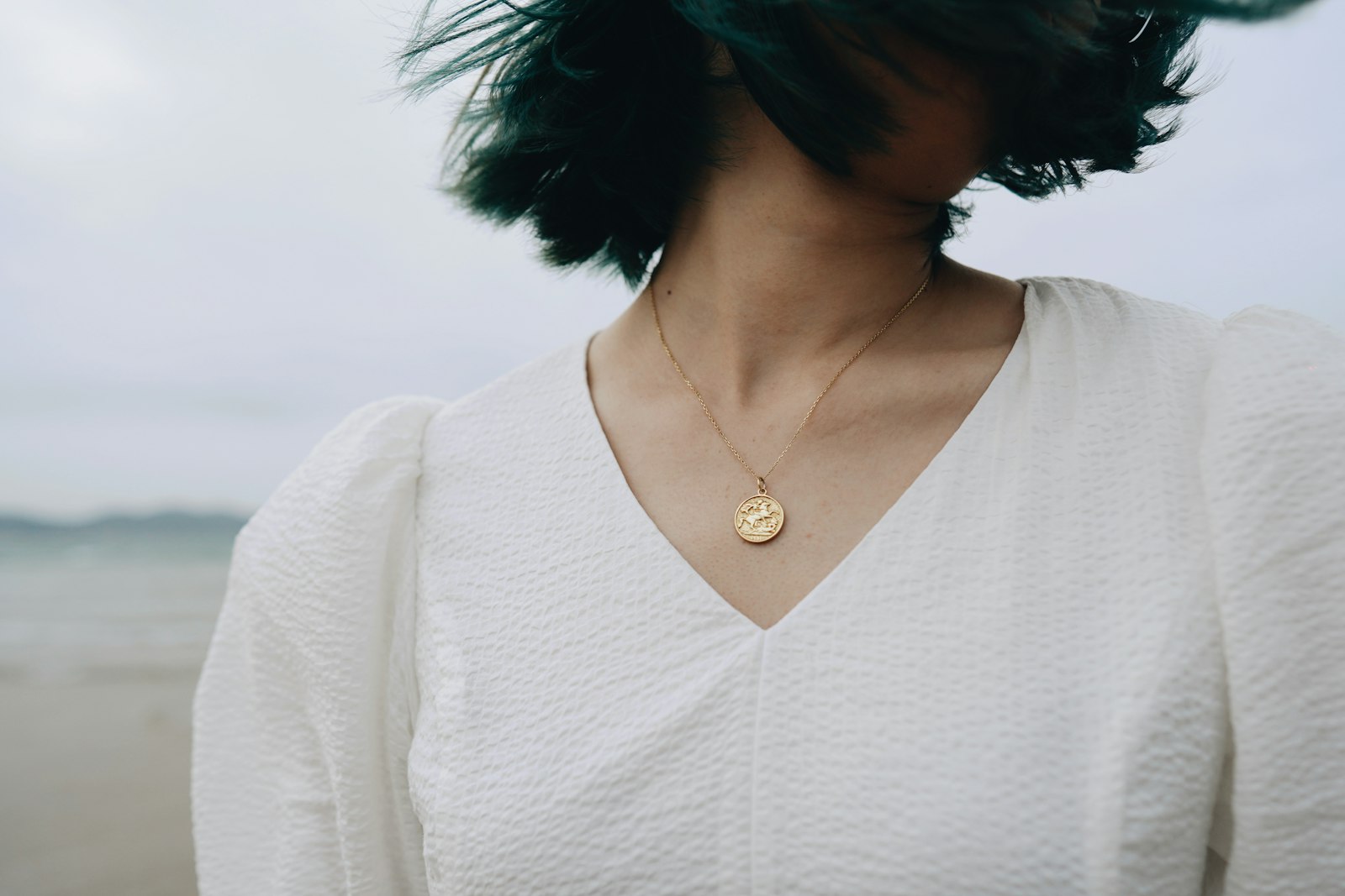 A delicate pendant necklace worn with a white blouse