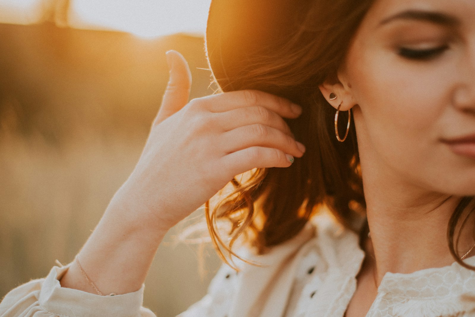 A woman touching her hoop earring in warm evening light